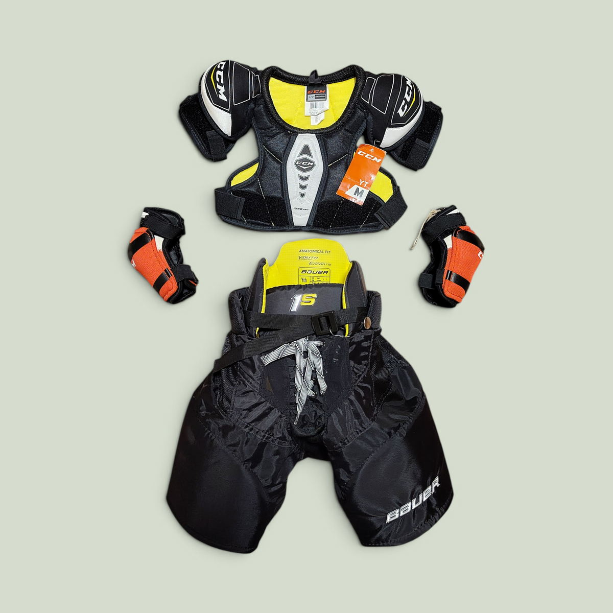 Rörelseboxen youth hockey gear set including CCM shoulder pads, Bauer hockey pants, and orange elbow pads