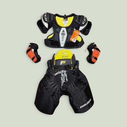 Rörelseboxen youth hockey gear set including CCM shoulder pads, Bauer hockey pants, and orange elbow pads